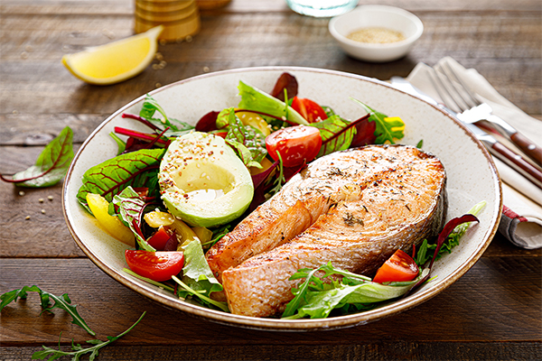 Salmon fish steak grilled, avocado and fresh vegetable salad with tomato, bell pepper and leafy vegetables. foods for your thyroid. Thyroid loving foods. Iodine. Selenium.